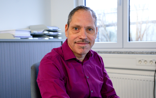 Hier sieht man einen freundlichen Mann im Büro, der ein Lilianes Hemd trägt. 