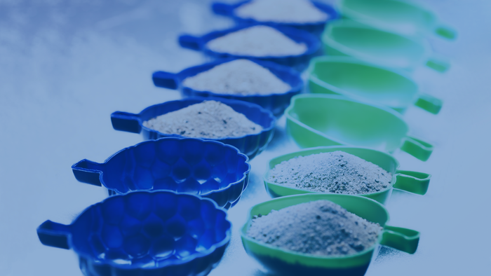 Mehrere blaue und grüne Schalen, gefüllt mit Pulver, sind in zwei Reihen angeordnet.