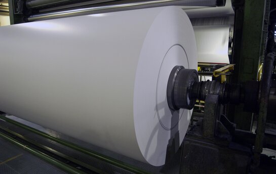 Große Papierrolle wird maschinell in Papierfabrik aufgewickelt