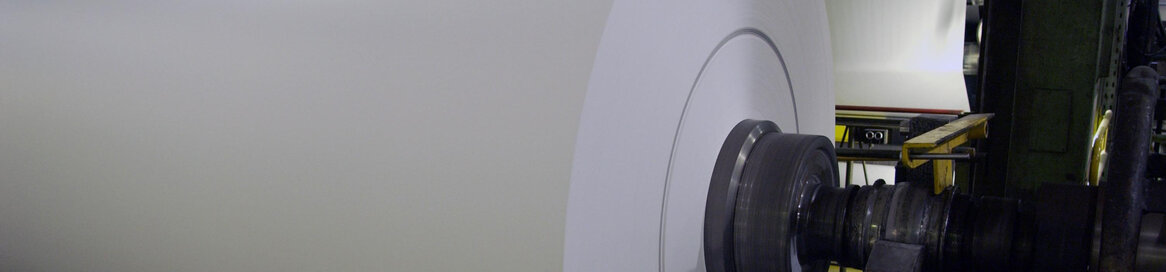 Große Papierrolle wird maschinell in Papierfabrik aufgewickelt