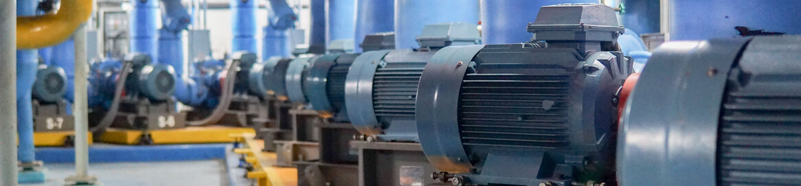 Reihen von Elektromotoren und farbigen Rohren in einer Pumpstation