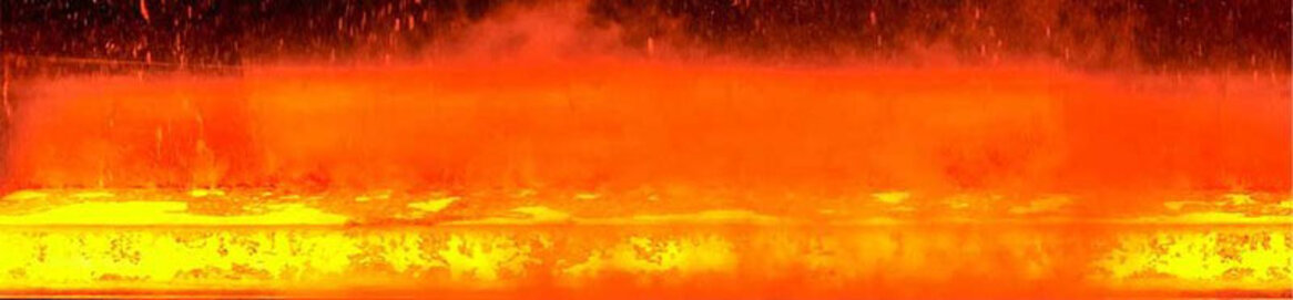 Rotglühender Stahl wird im Walzwerk mit Wasserstrahlen gekühlt