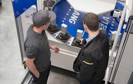 Zwei Männer betrachten und diskutieren eine industrielle Maschinensteuerung.