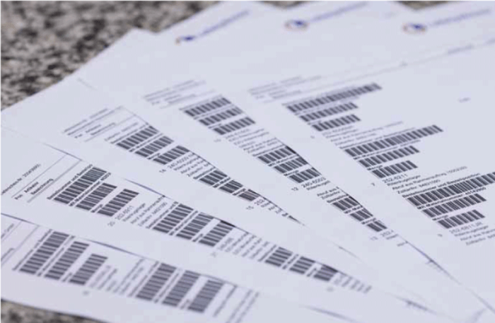 Mehrere gestapelte Dokumente mit Barcodes auf einer Oberfläche.