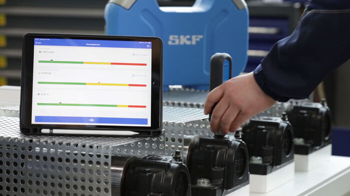 Ein Tablet zeigt Messergebnisse auf einem Metallgerät, während eine Person daran arbeitet.