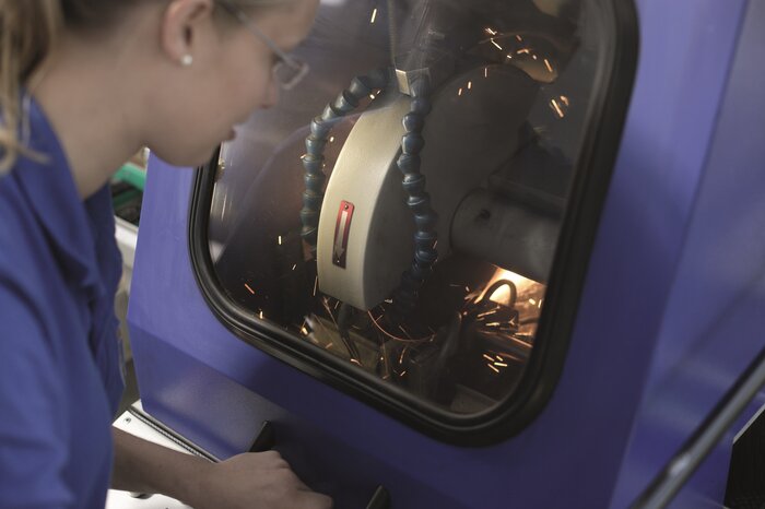 Eine Person bedient eine Maschine, die Funken erzeugt, in einem technischen Service-Center.