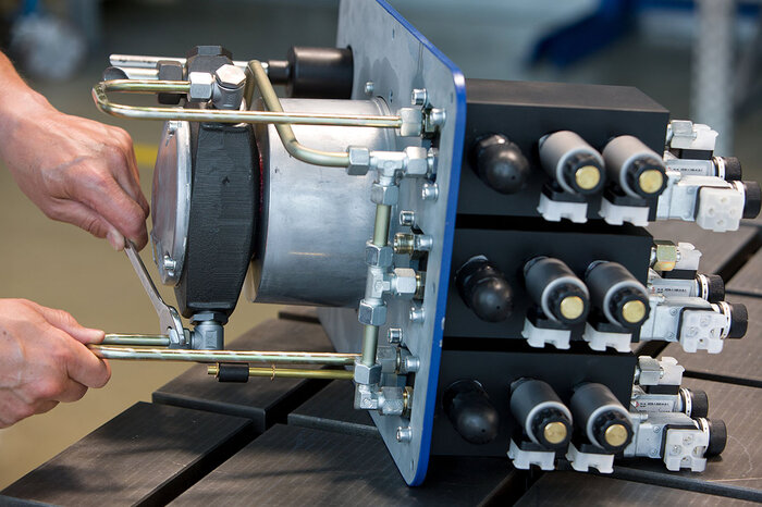 Eine Person arbeitet mit einem Schraubenschlüssel an einem hydraulischen Aggregat.