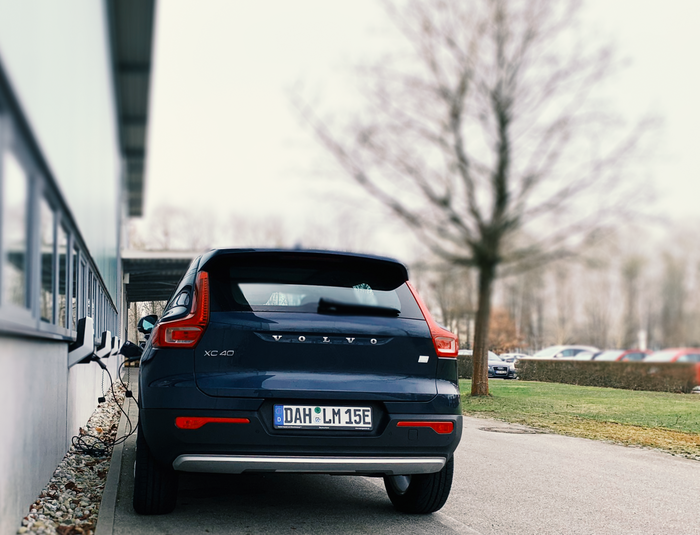 Ein Elektroauto lädt an einer Ladestation neben einem Gebäude.