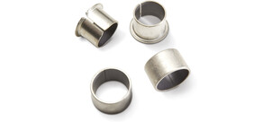Vier metallische Gleitlager und Buchsen in verschiedenen Formen auf weißem Hintergrund.
